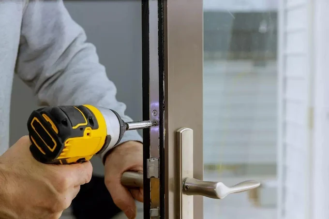Serrurier professionnel installant une serrure de porte avec visseuse
